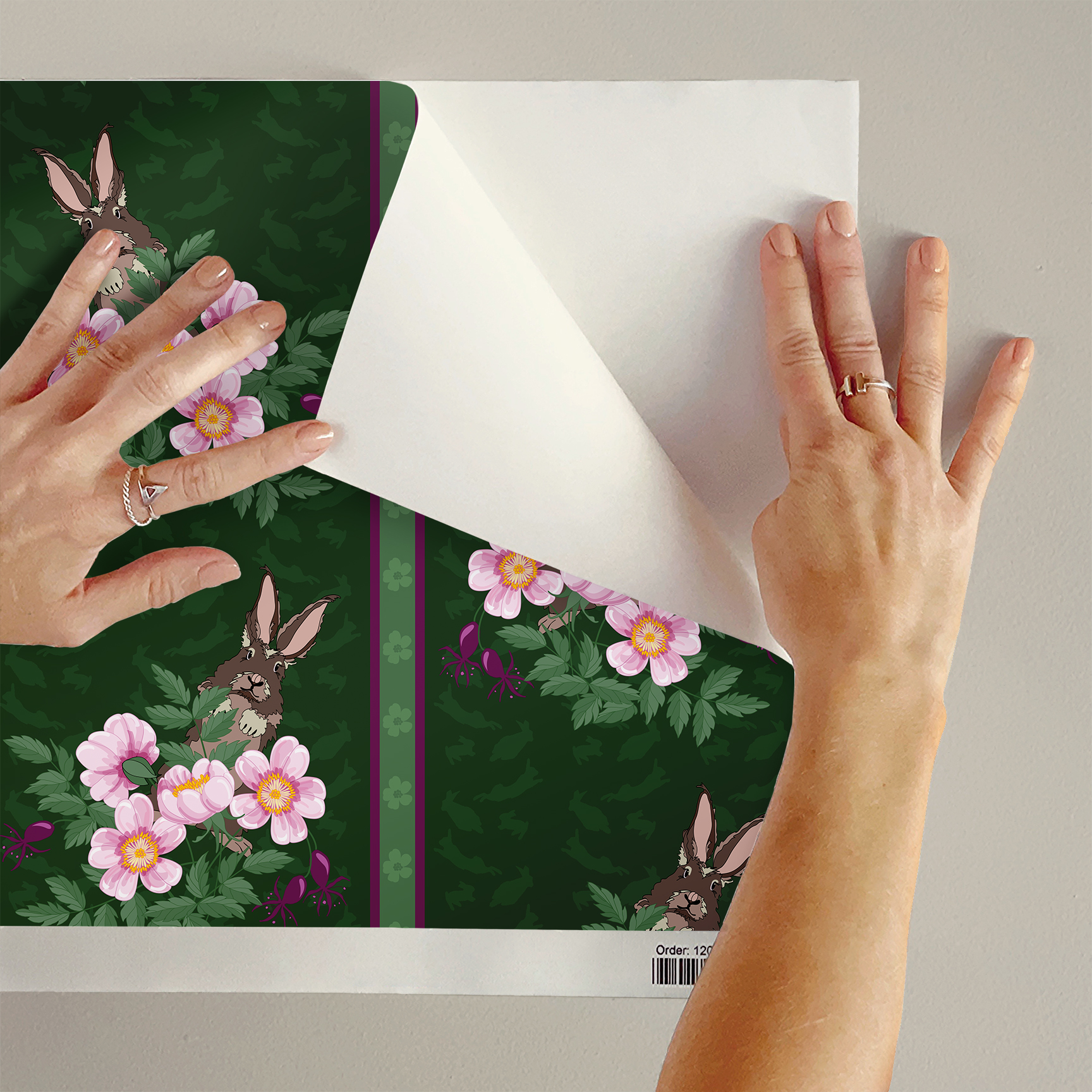 The artwork depicts a stylized brown hare partially concealed behind a cluster of green leaves and pink flowers with yellow centers. The background is dark green with subtle leafy patterns. Two vertical stripes—one dark purple and one green with small floral motifs—run along the left side, contrasting with the otherwise naturalistic elements. The composition balances the lively flora and fauna with a decorative, patterned design.